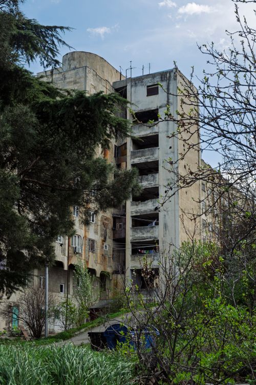 Free An old Soviet-style apartment building in Tbilisi, Georgia, surrounded by lush greenery. Stock Photo