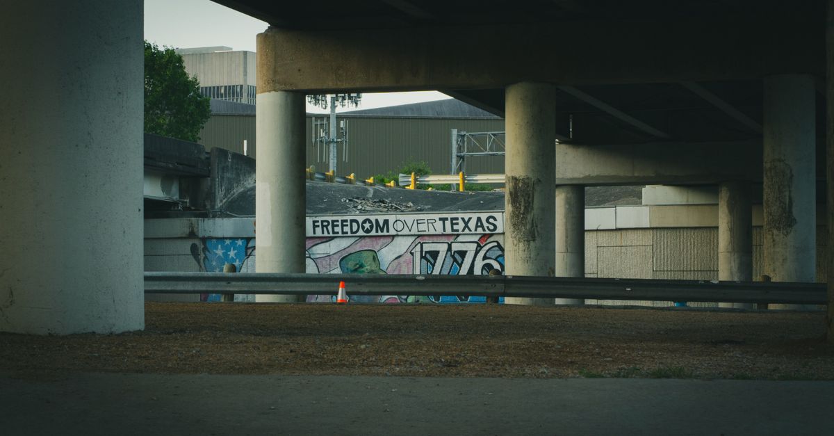 Graffiti art featuring 'Freedom Over Texas' beneath a concrete bridge in Houston.