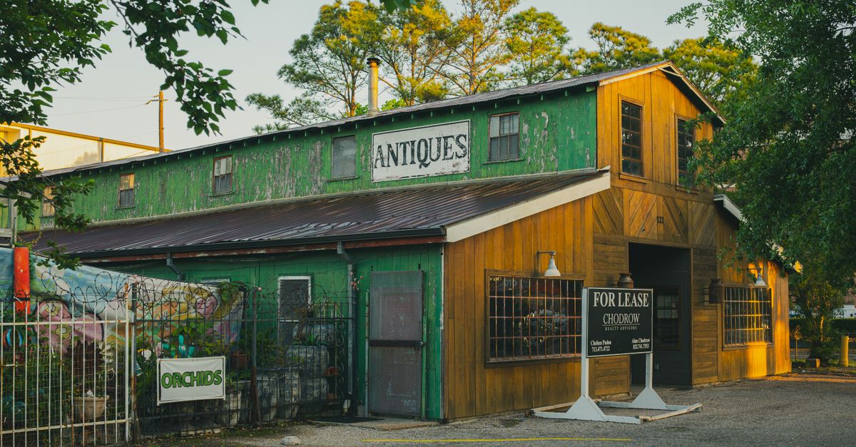 Rustic green and yellow antique shop exterior in Houston, Texas, with 'For Lease' sign.