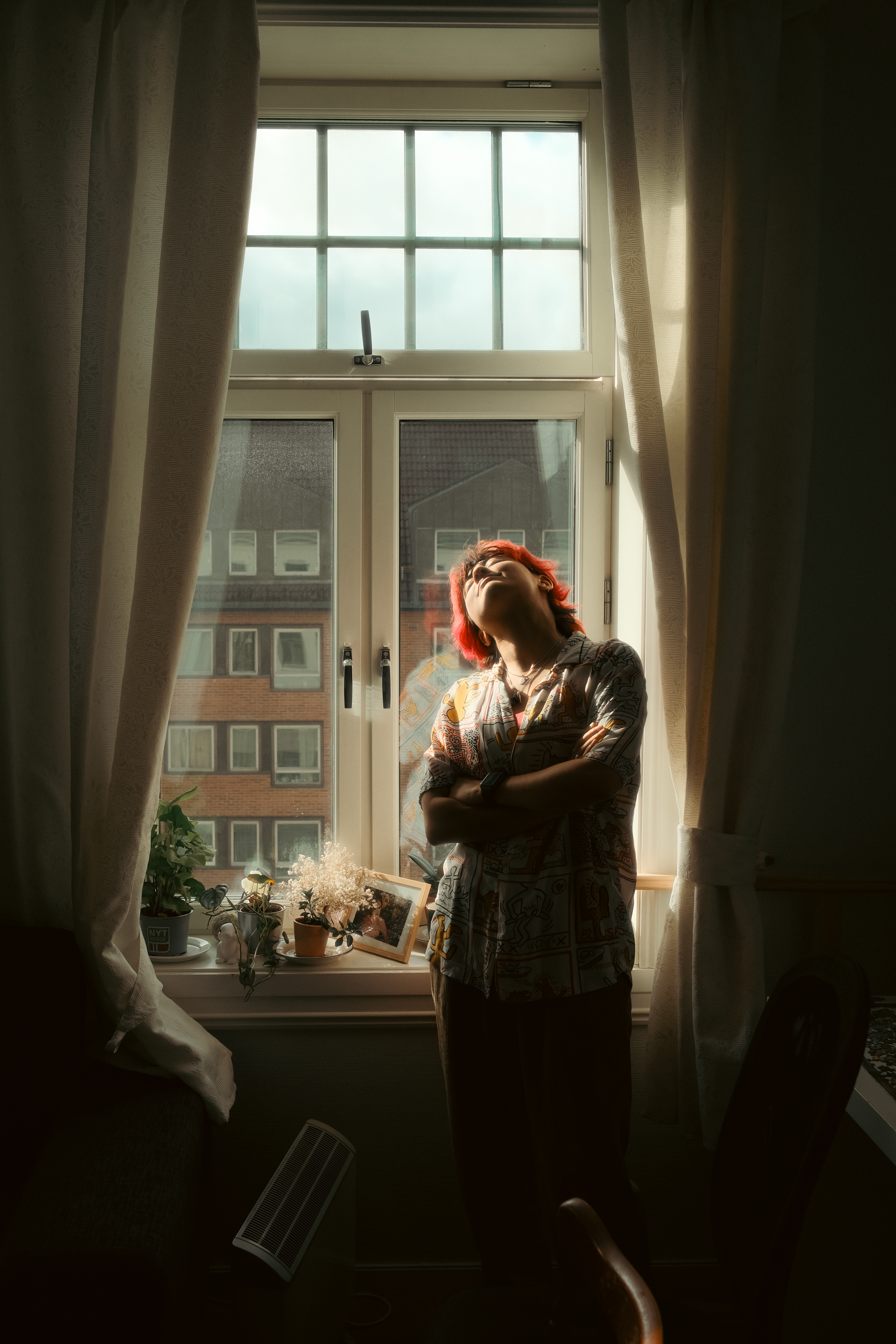 Contemplative Woman Standing by a Window in Sunlight · Free Stock Photo