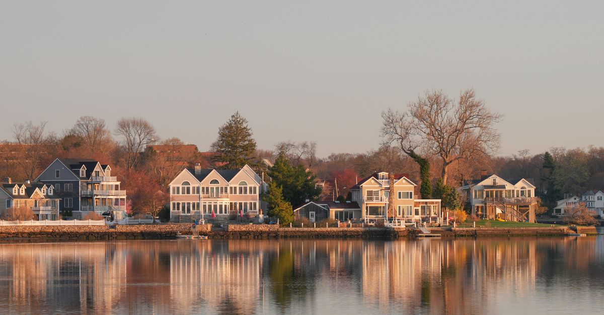 Scenic view of waterfront homes in Stamford, Connecticut at sunrise, with reflections on calm waters.