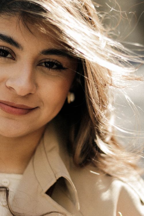 Free Close-up portrait of a smiling woman with sunlit hair, capturing warmth and joy. Stock Photo