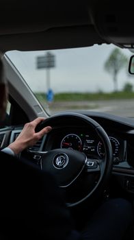 View from driver's seat showing car dashboard and steering wheel. Outdoors scene.