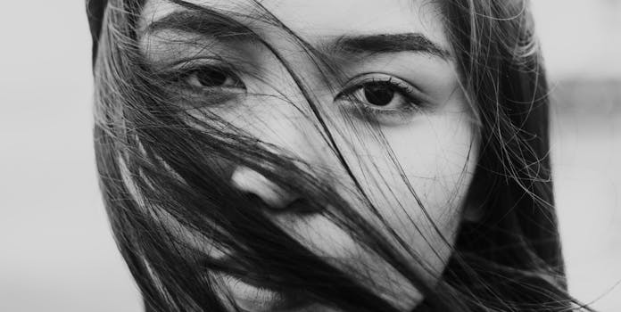 一幅引人注目的黑白肖像，描绘了一位头发随风飘扬的女子