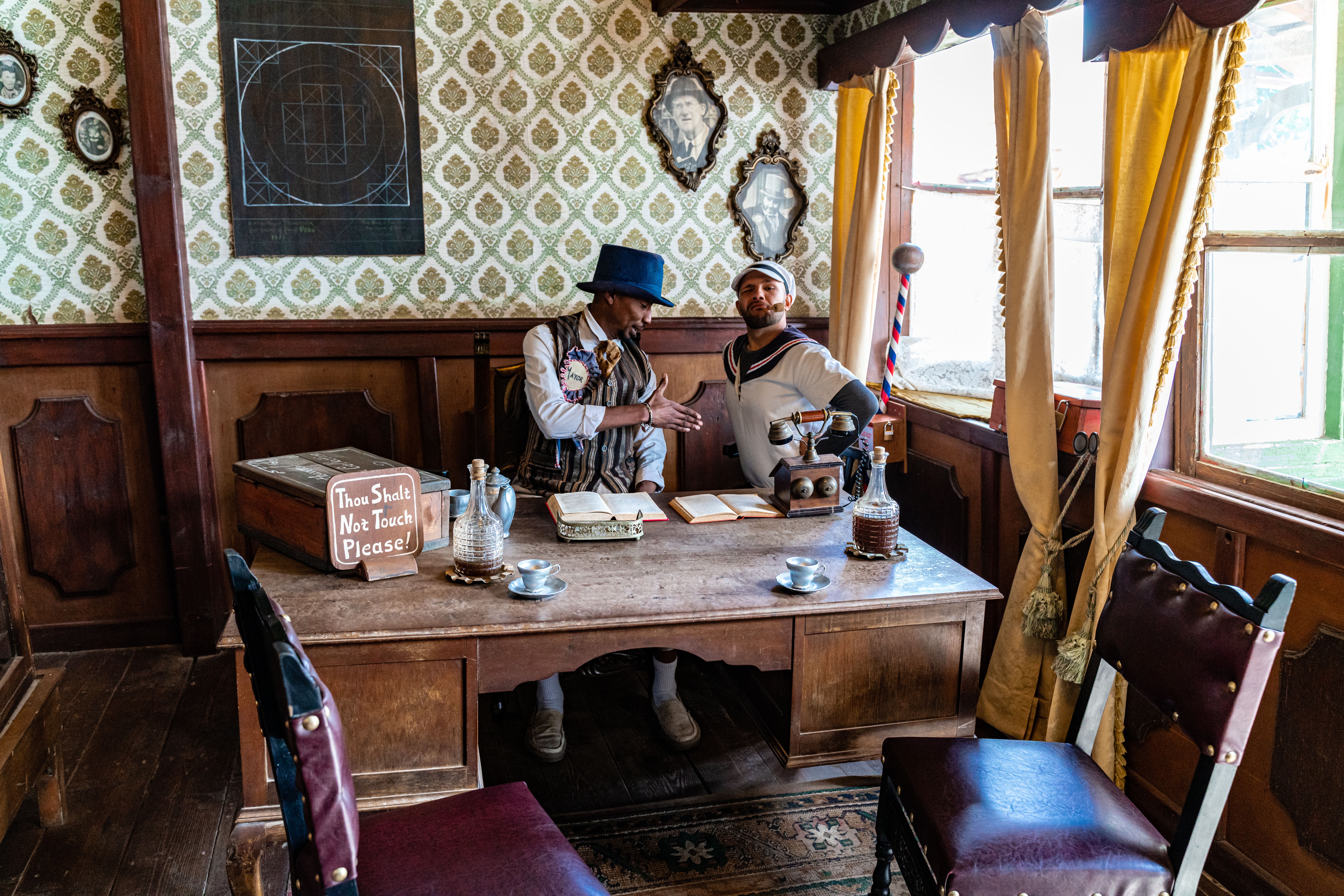 A vintage styled interior depicting a scene from Popeye Village in Malta with two figures.