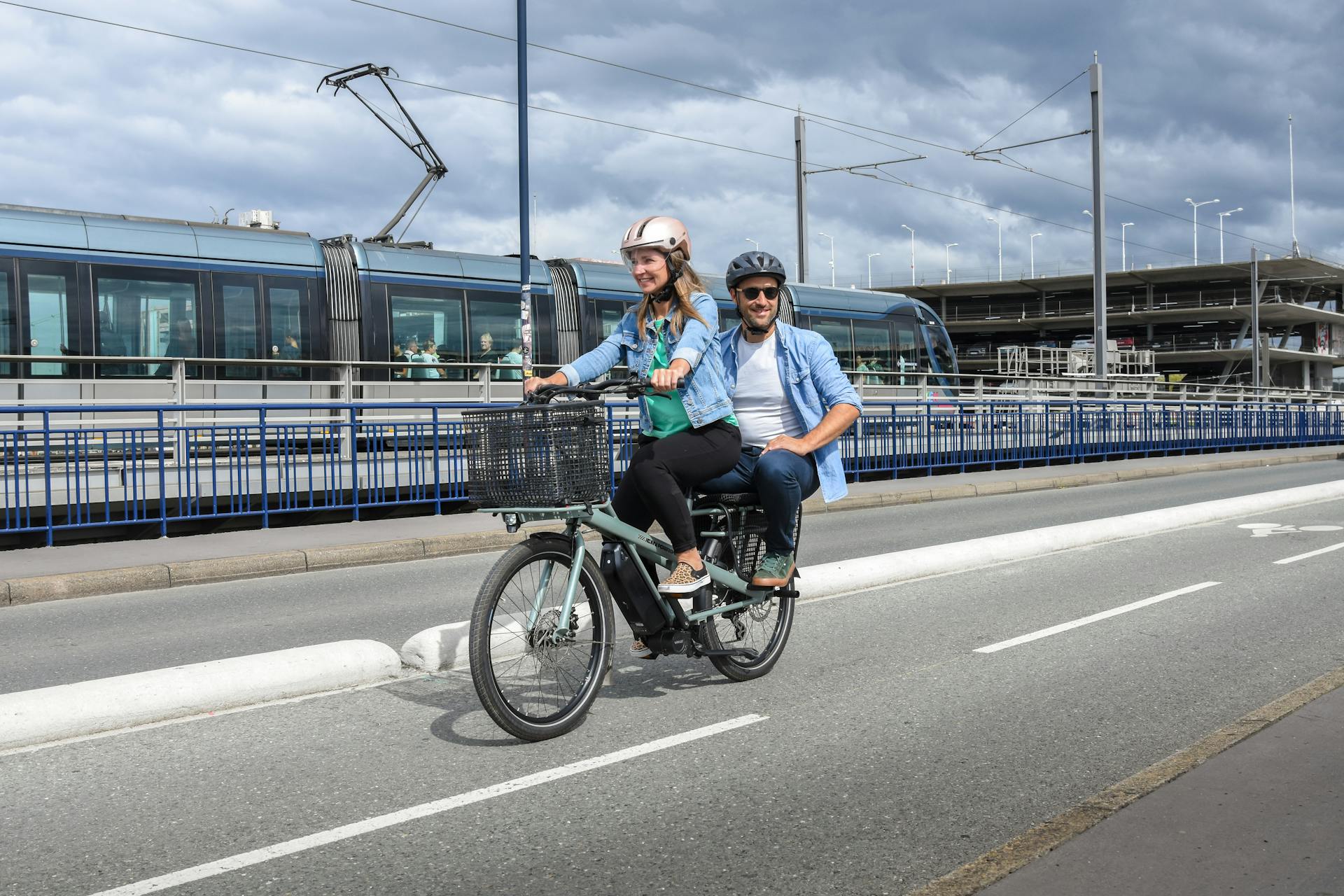 Couple enjoying a ride on a cargo bike in Bordeaux, France, near tram tracks.