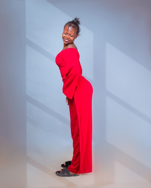 Free Confident woman posing in a vibrant red dress with a joyful smile. Stock Photo
