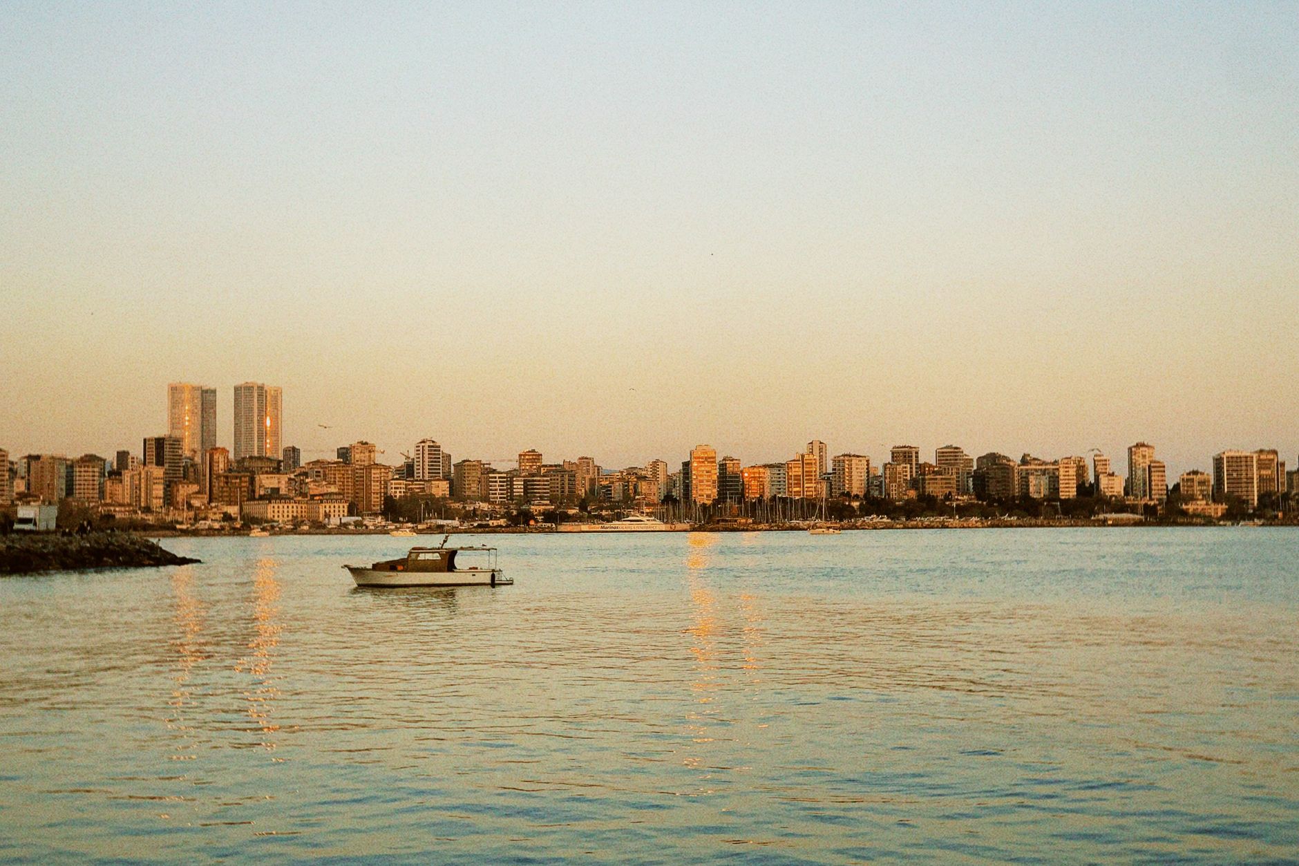 A serene view of the Beirut skyline with a boat on calm waters during sunset. — photo by Eyüpcan Timur / Pexels