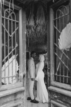 A romantic black and white photo of a couple holding hands at their wedding.