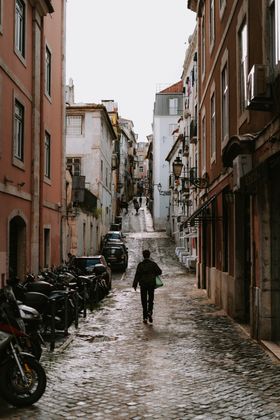 A traveller walking a cobbled street in Lisbon's historic district — photo by Riccardo Toso on Pexels