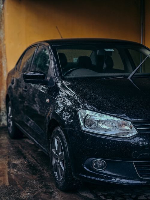 Free A sleek black Volkswagen sedan parked in a driveway on a rainy day, showcasing auto design elegance. Stock Photo