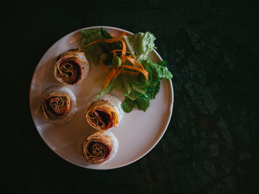 Close-up of a sliced turkey bacon ranch pinwheel showing distinct layers of turkey, bacon, and lettuce.