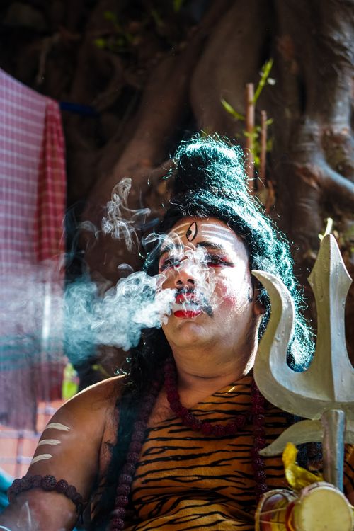 Free Person in cultural attire performing ritual with a trident and smoke. Stock Photo