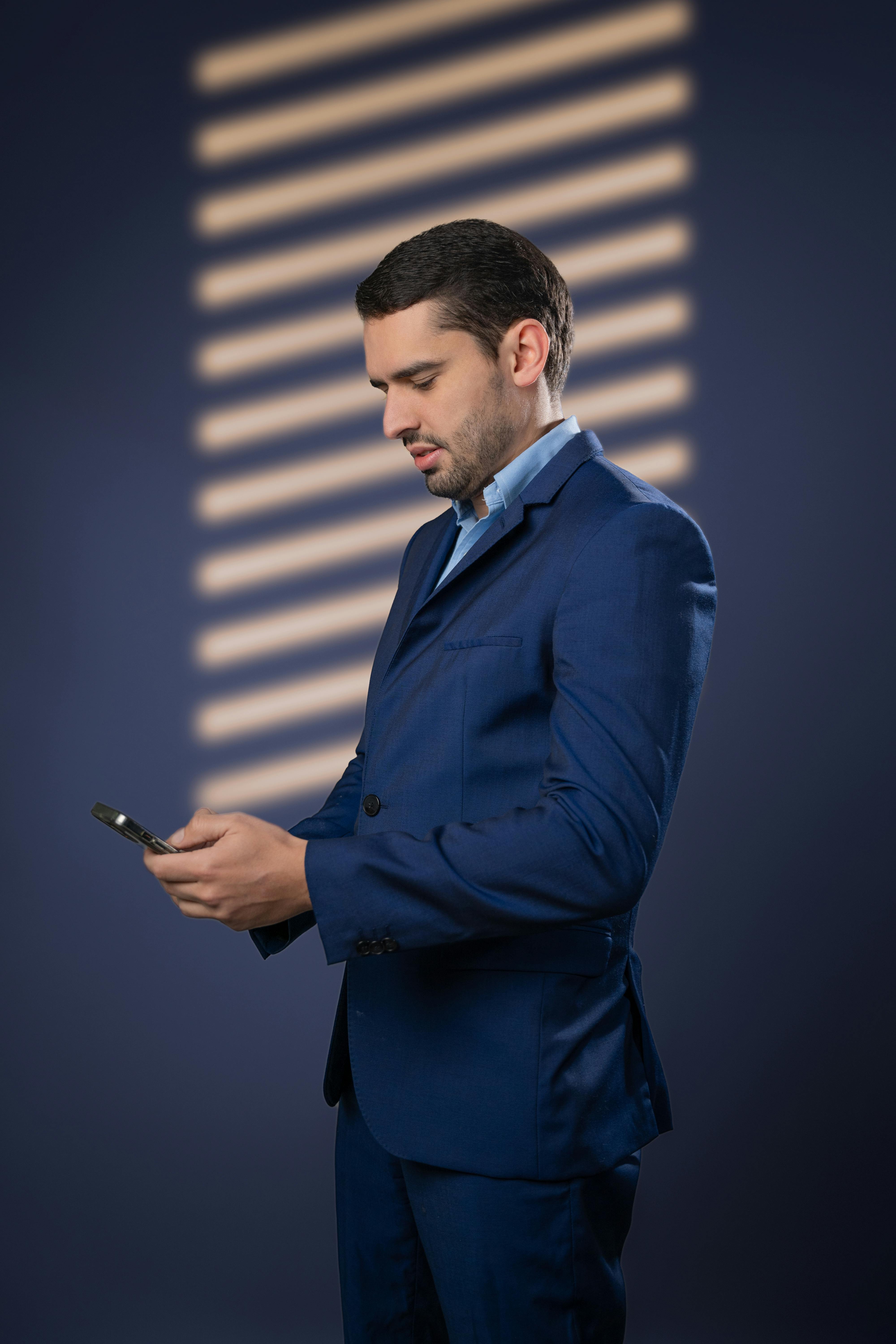 Gratis Un hombre profesional con traje azul revisa su teléfono inteligente en el interior. Foto de stock