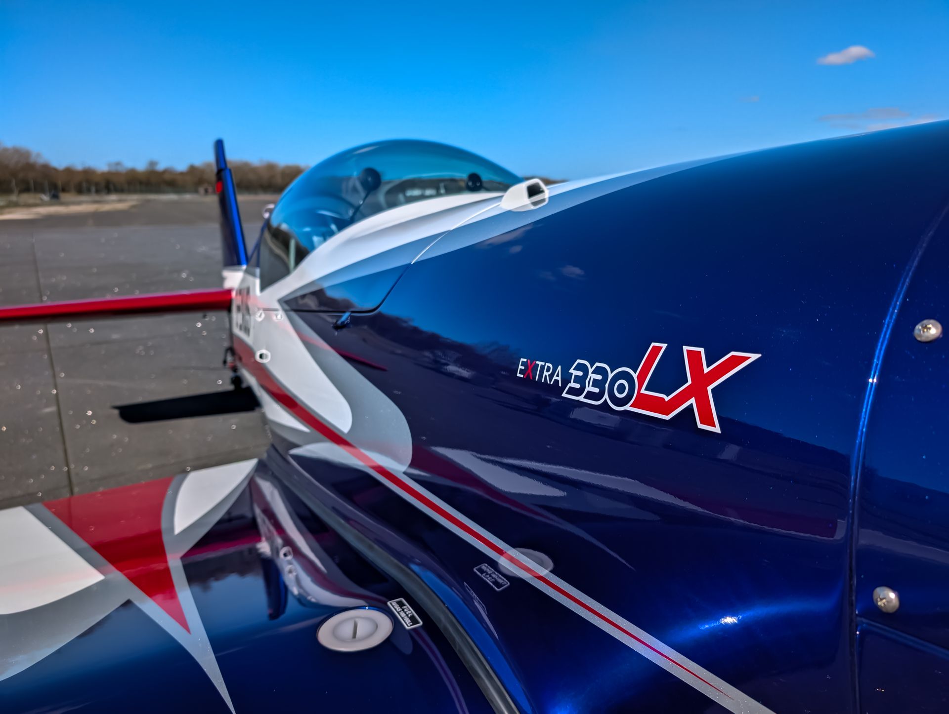 Detailed shot of an Extra 330LX aerobatic airplane on a sunny day, showcasing its vibrant design.