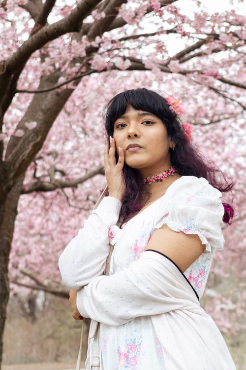 Free A serene woman in vintage dress poses under blooming cherry blossoms in spring. Stock Photo