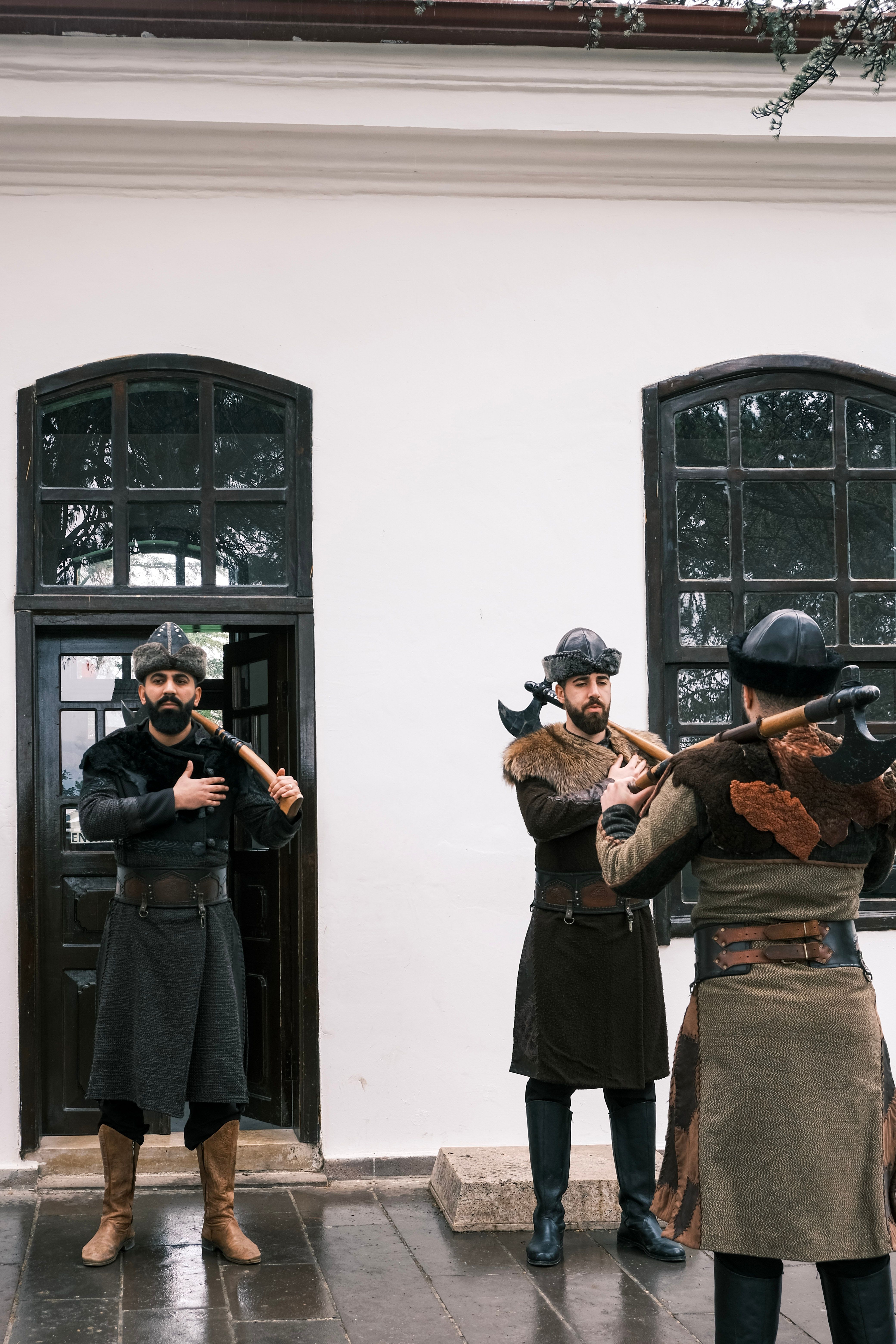 Three historical reenactors pose with axes, evoking Ottoman era soldiers outdoors.