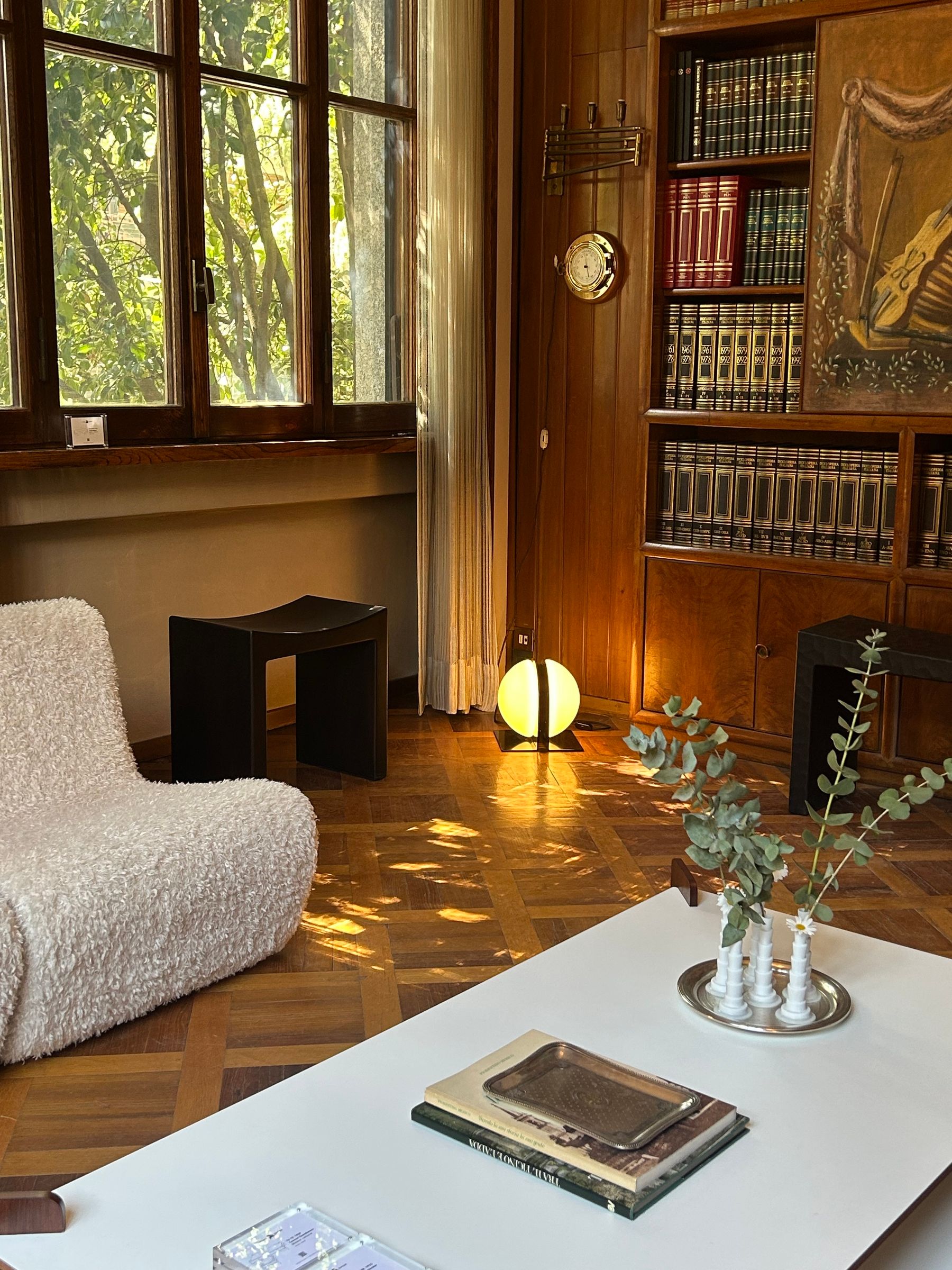 Warm mid-century modern living room with wood furniture, low seating, plants and layered ambient light