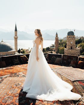 Bride poses in a flowing white gown on a Turkish rooftop with stunning architectural and seaside views.