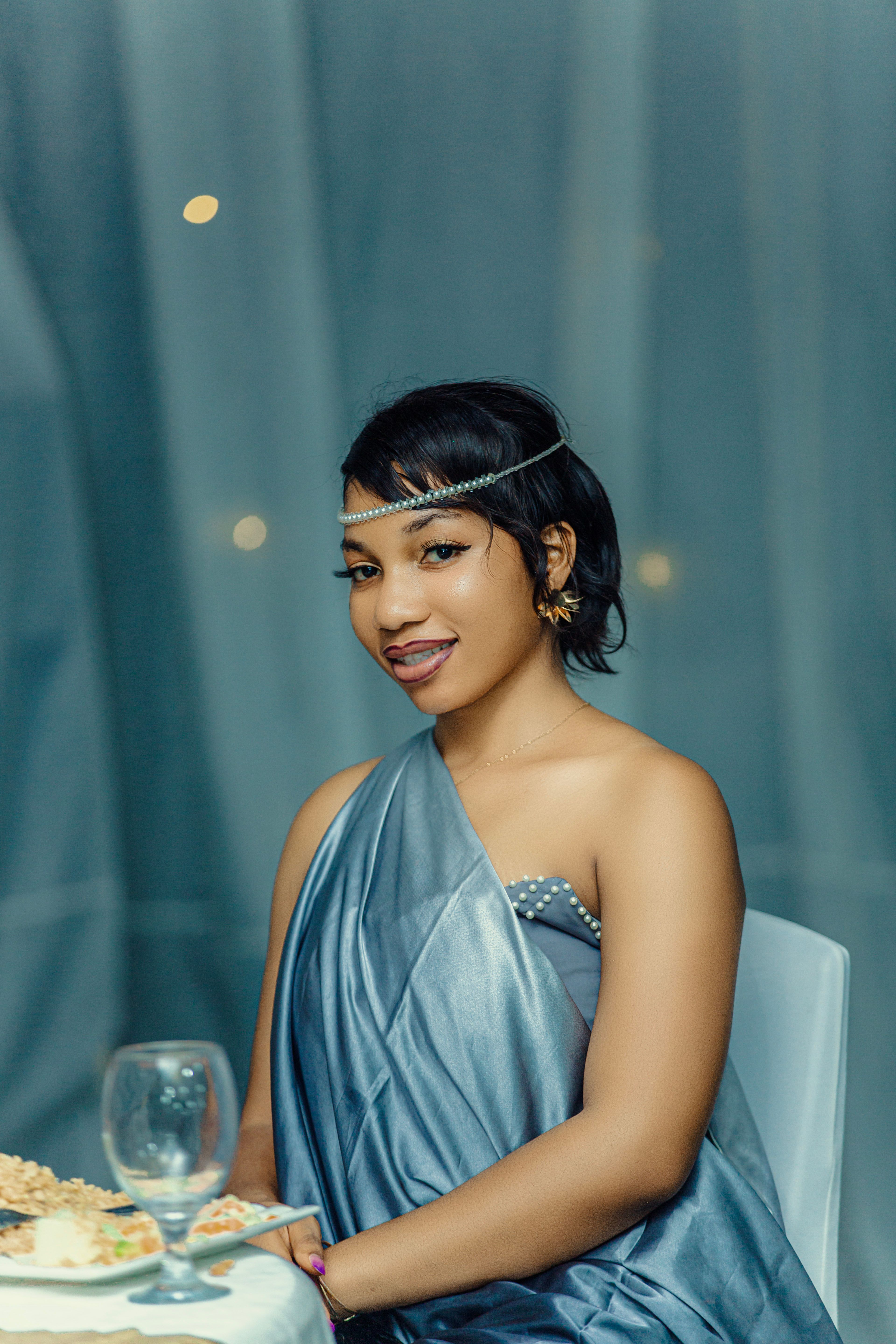Free Elegant woman in blue evening gown sitting at formal event table ...