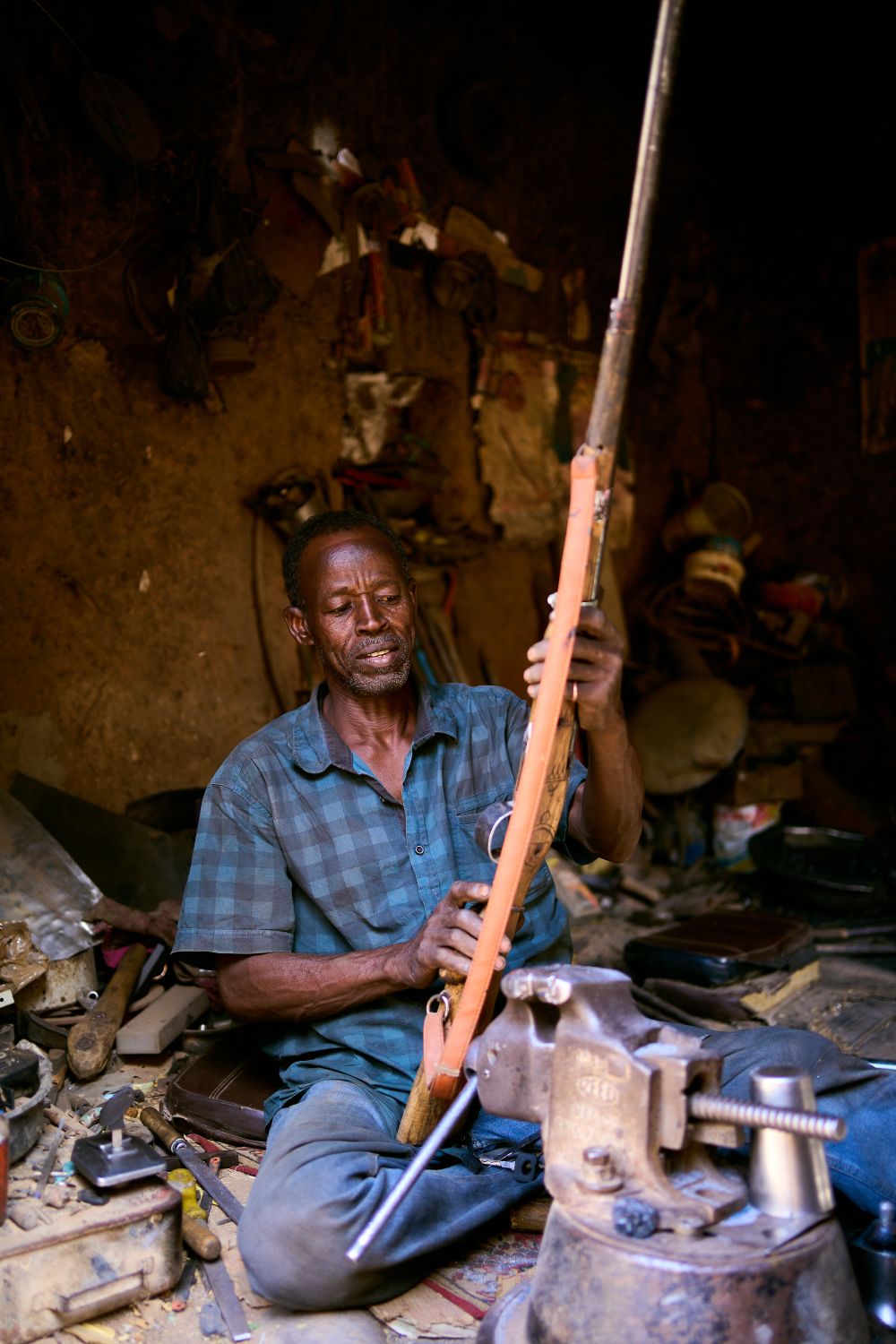 Tradesman working a steel component at a bench in a fabrication shop.