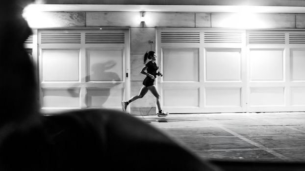 A woman running at night in Buenos Aires, showcasing urban life in black and white.