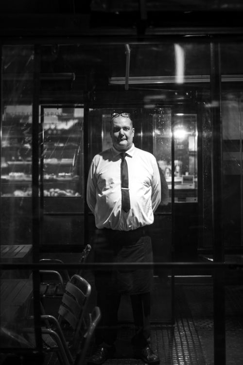 Free Black and white shot of a man standing in a cafe in Buenos Aires at night. Stock Photo