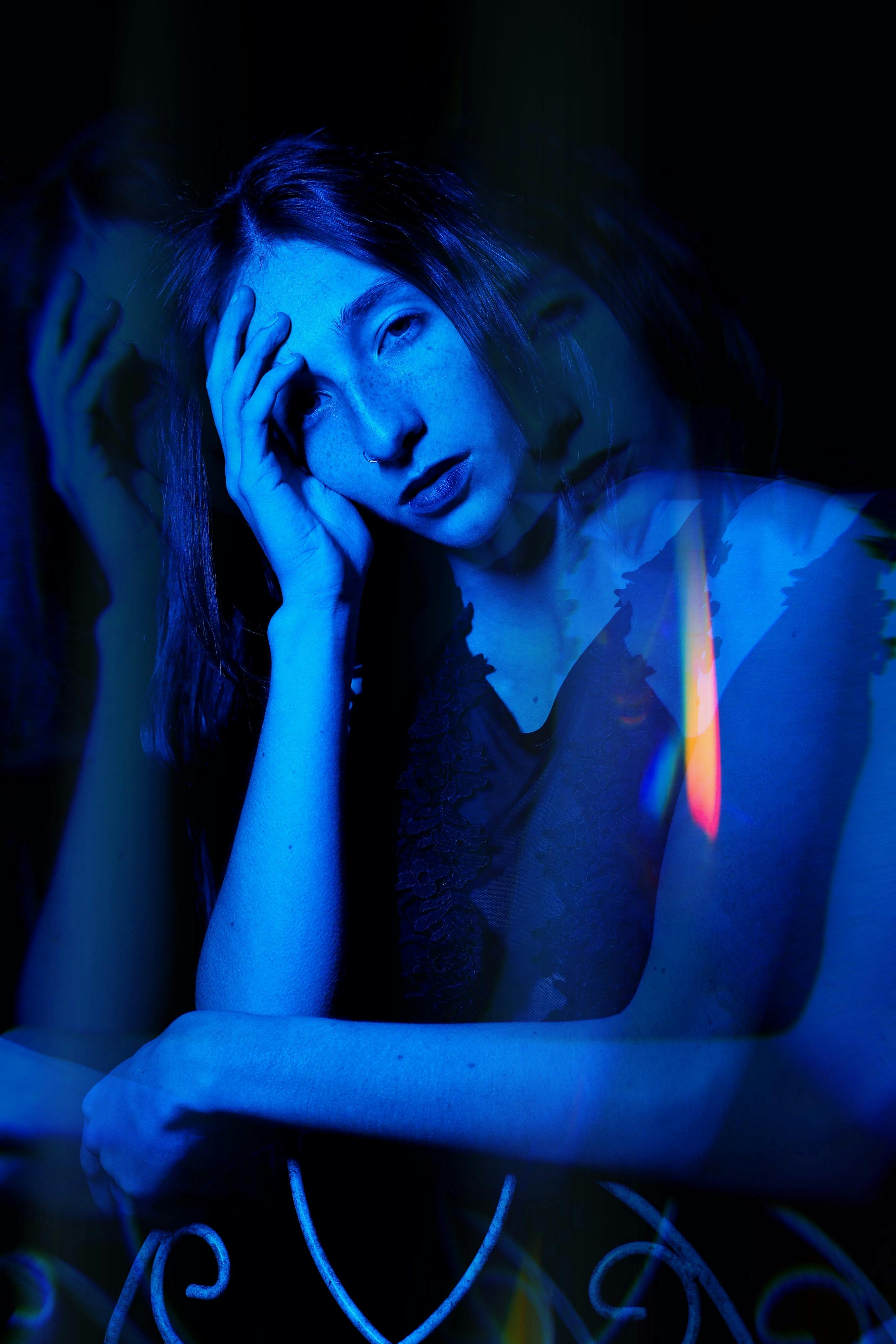 Artistic blue double exposure portrait of a woman with dramatic lighting.