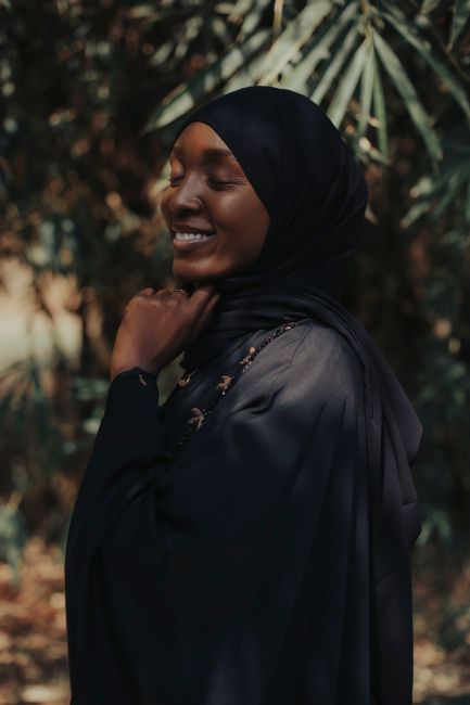 Elegant portrait of a woman smiling amidst natural foliage in Nigeria, showcasing cultural and nature vibes.