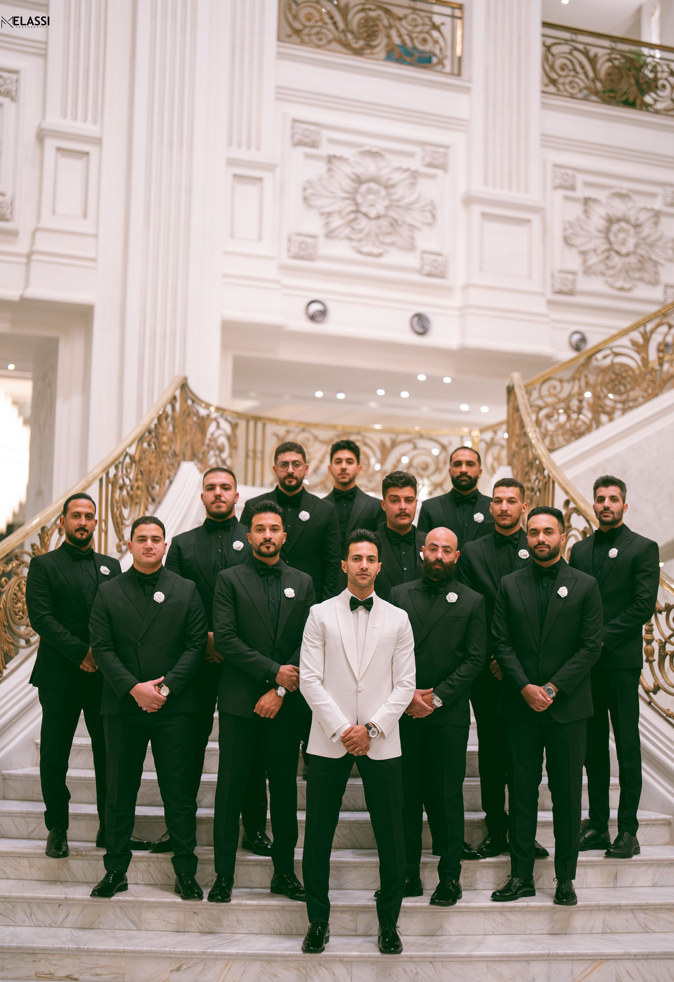 Group of groomsmen in suits on a luxurious staircase, showcasing wedding elegance.