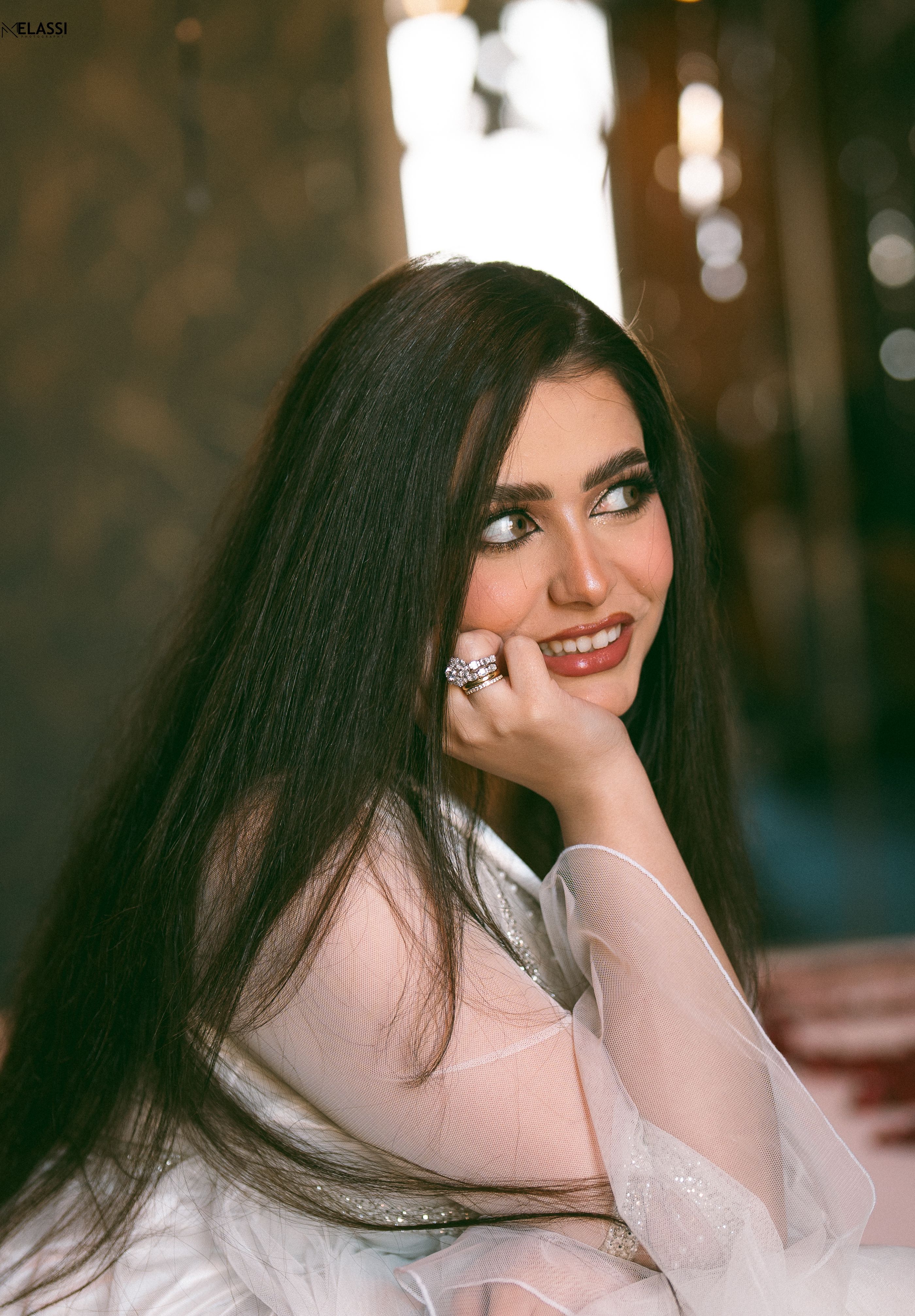 Portrait of a smiling woman with long hair in elegant attire, indoors.