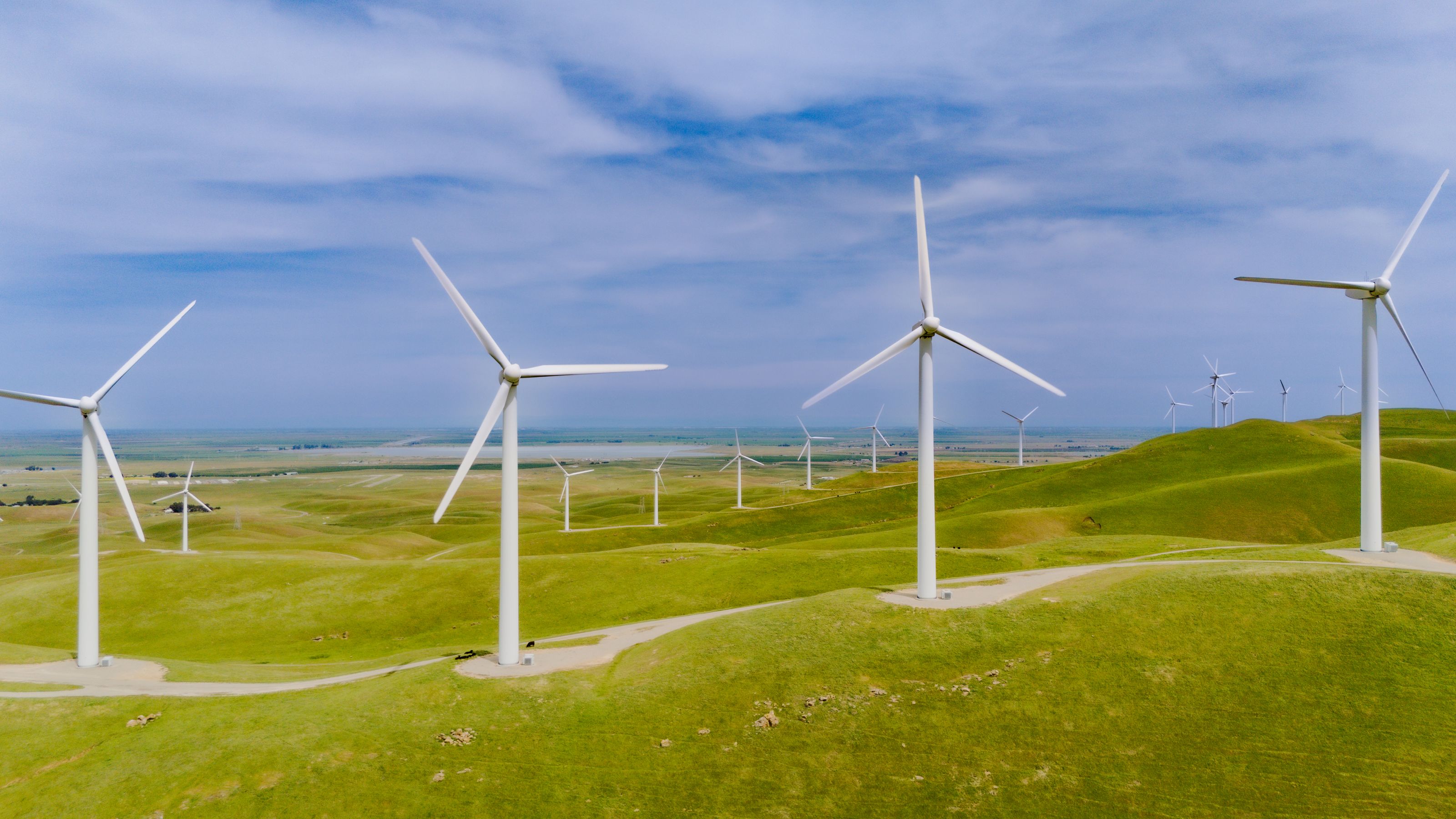 Aerial view of wind turbines on lush green hills in California.