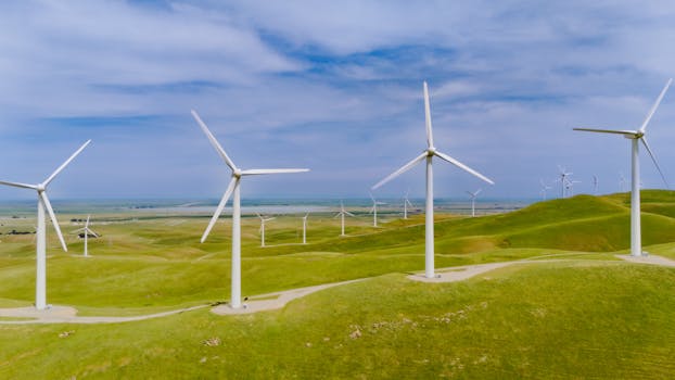 Aerial view of wind turbines on lush green hills in California.