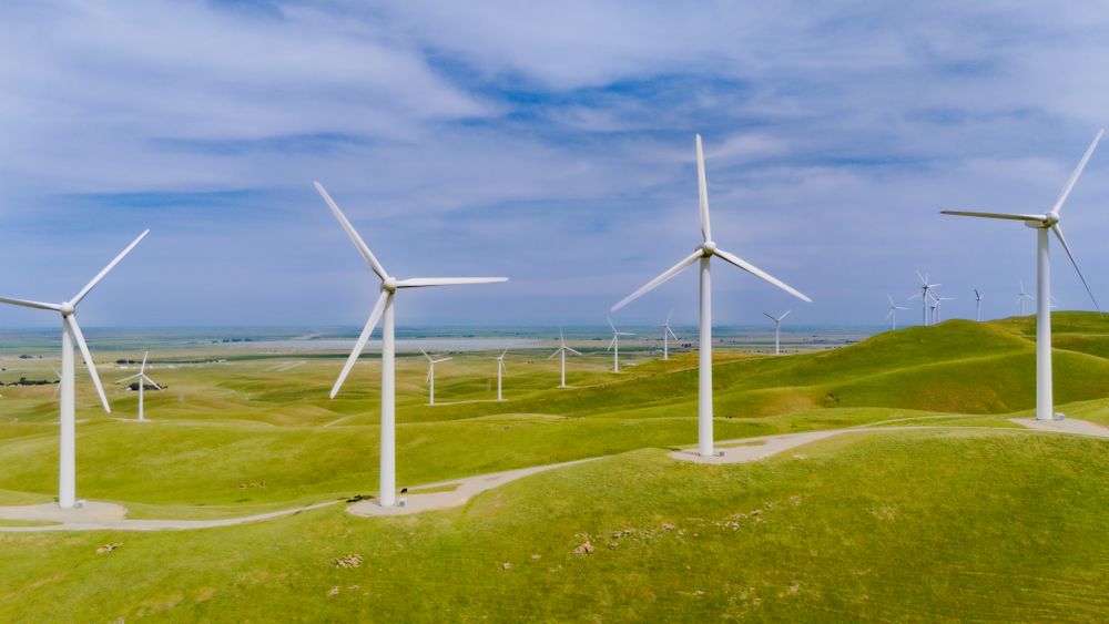 Wind turbines standing across rolling green hills