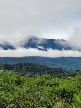 Breathtaking aerial view of lush green mountains and clouds in West Java, Indonesia.