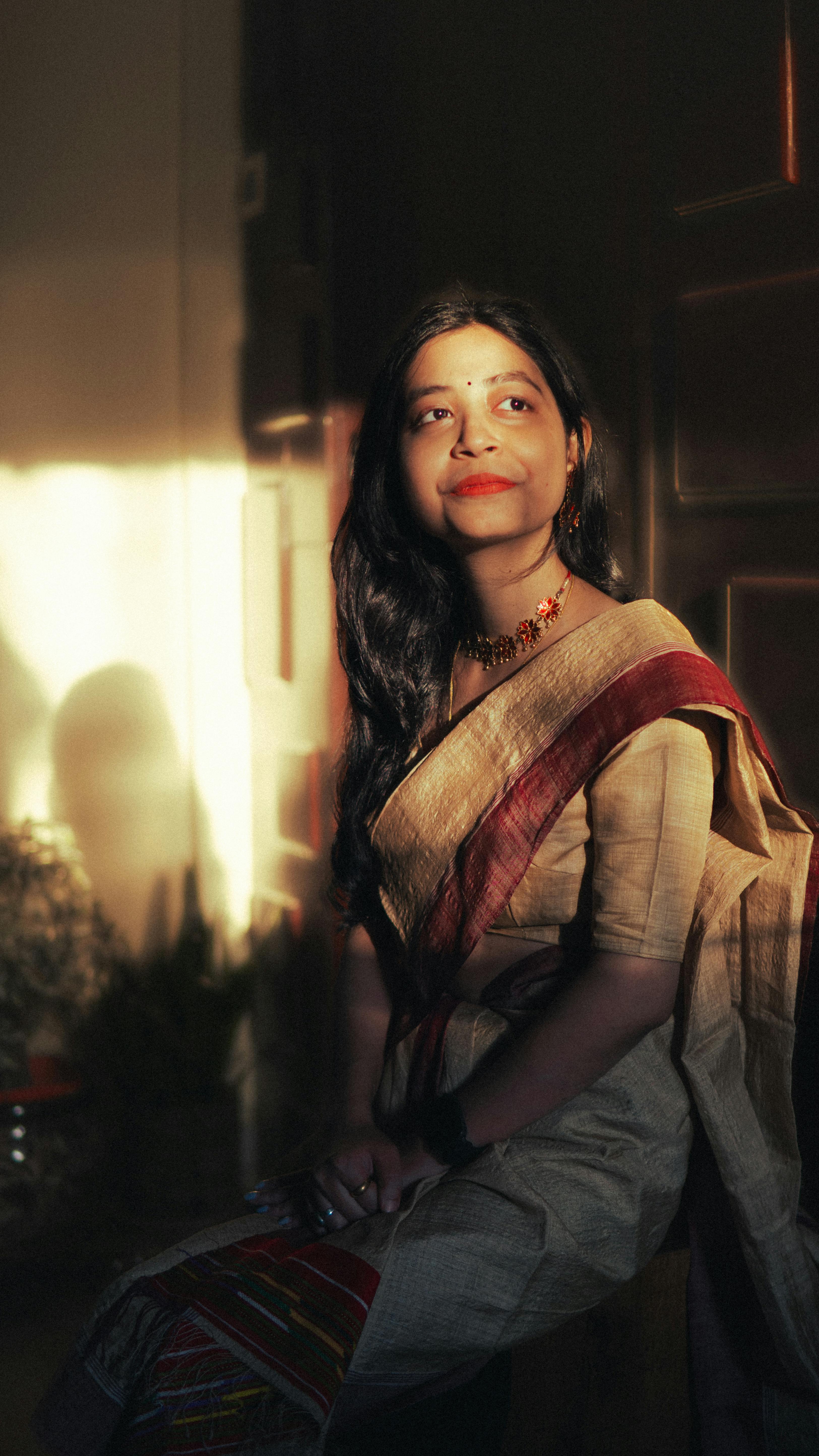 A woman in traditional attire gazes peacefully in soft sunset light, embodying Indian aesthetics.