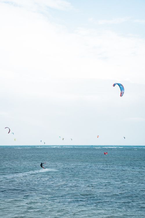Free Kitesurfers enjoy the sunny coastal waters, capturing the thrill of adventure and freedom. Stock Photo