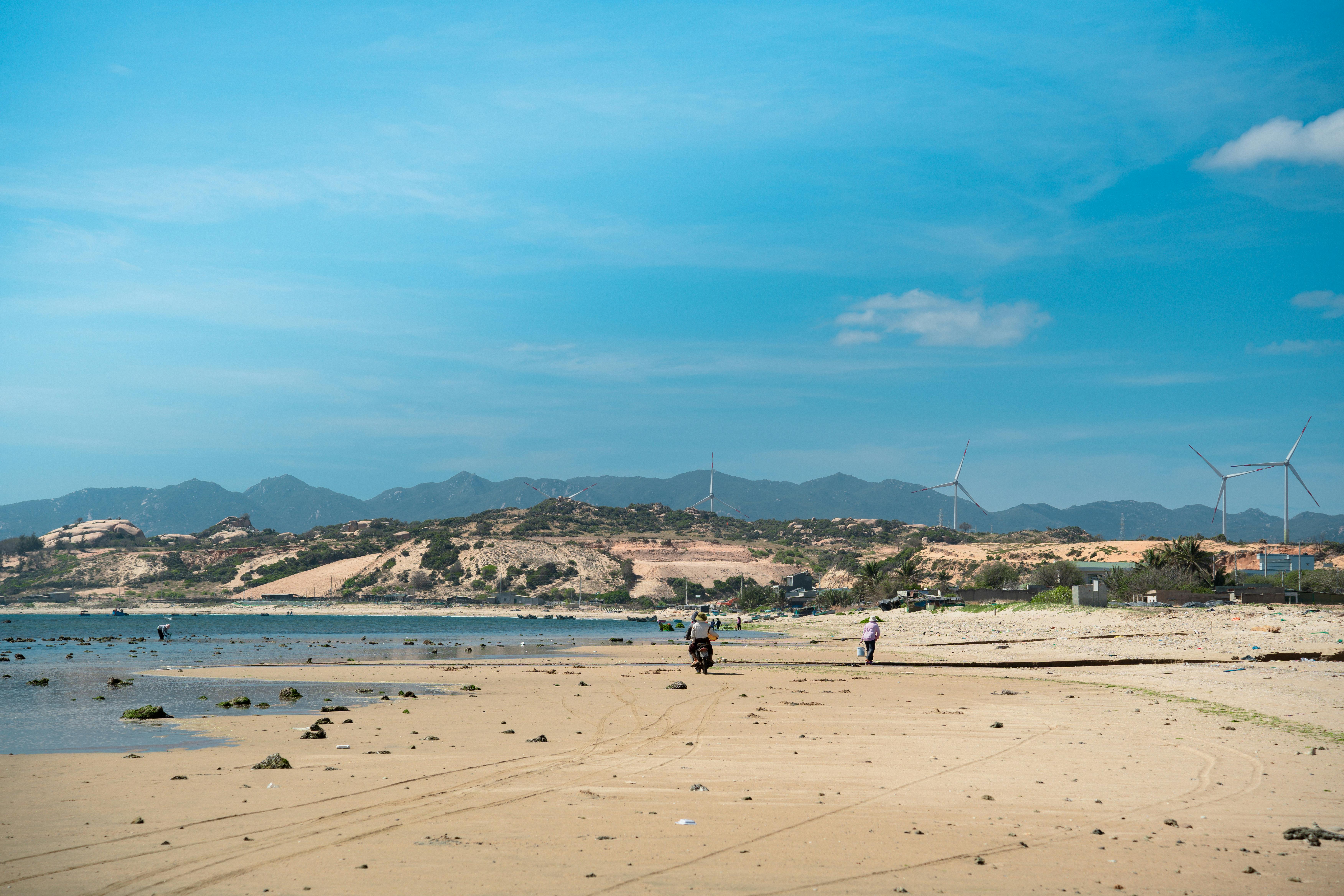 Peaceful coastal landscape in Vietnam with sand dunes and wind turbines.