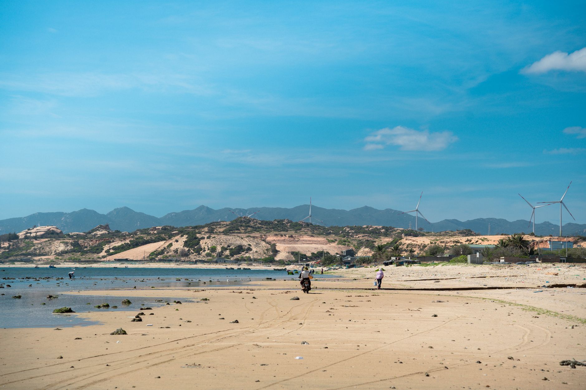 Peaceful coastal landscape in Vietnam with sand dunes and wind turbines.