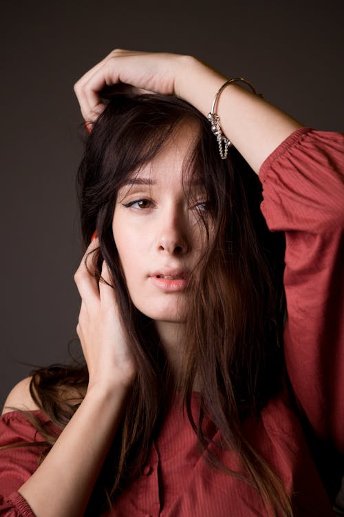 Free Close-up Of A Young Woman With Tousled Hair Wearing Red Long-sleeved Top Stock Photo