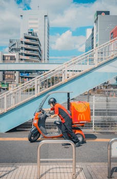 McDonald's delivery scooter and rider in urban Tokyo, Japan with modern architecture backdrop.