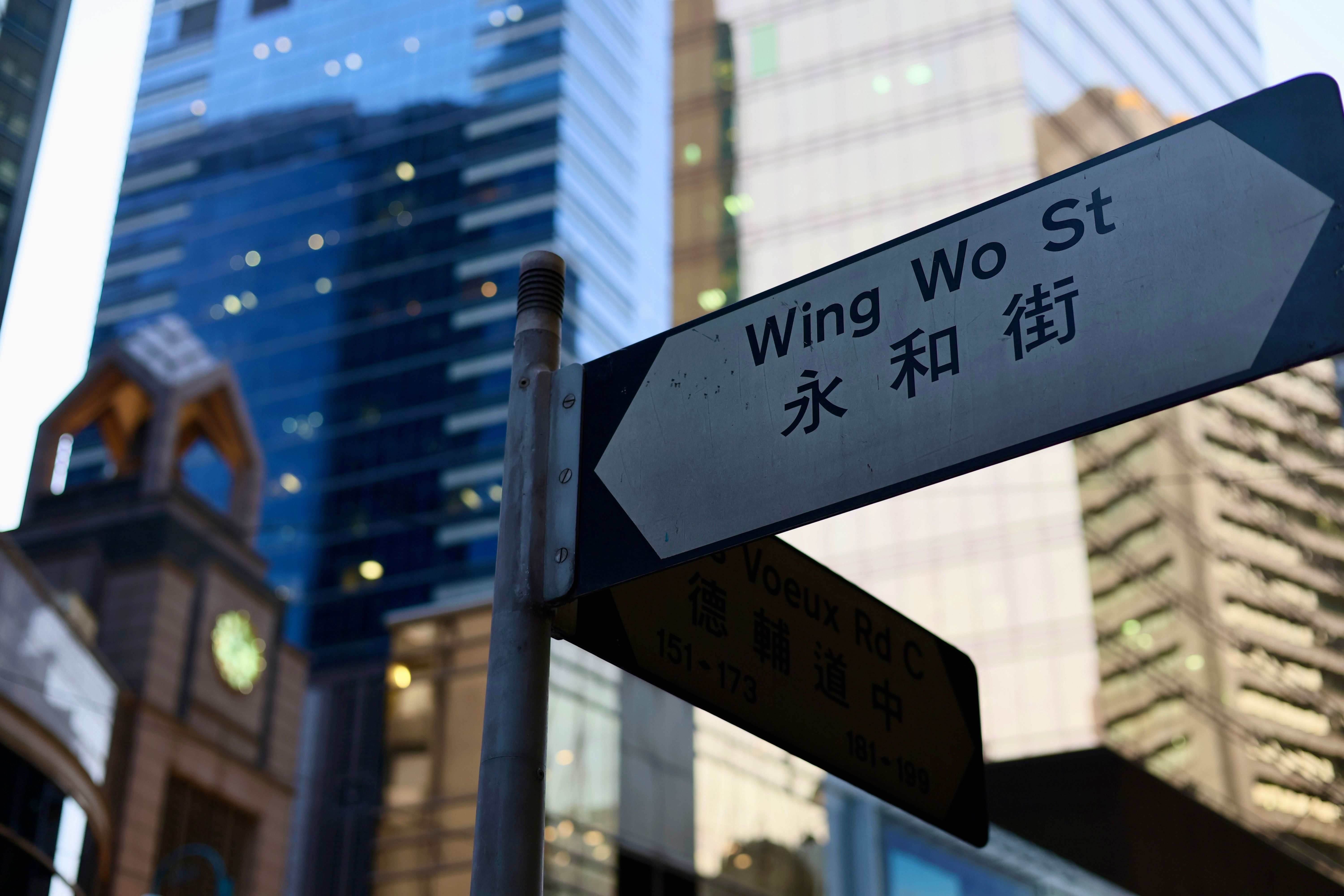 A street sign stands among towering skyscrapers in a dense urban area.