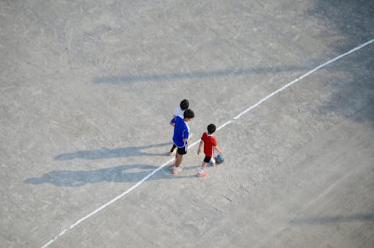 Children playing soccer on an outdoor field, aerial view.