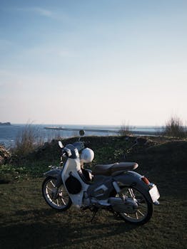 Classic motorcycle parked by a scenic coastal road at sunset, overlooking the ocean.