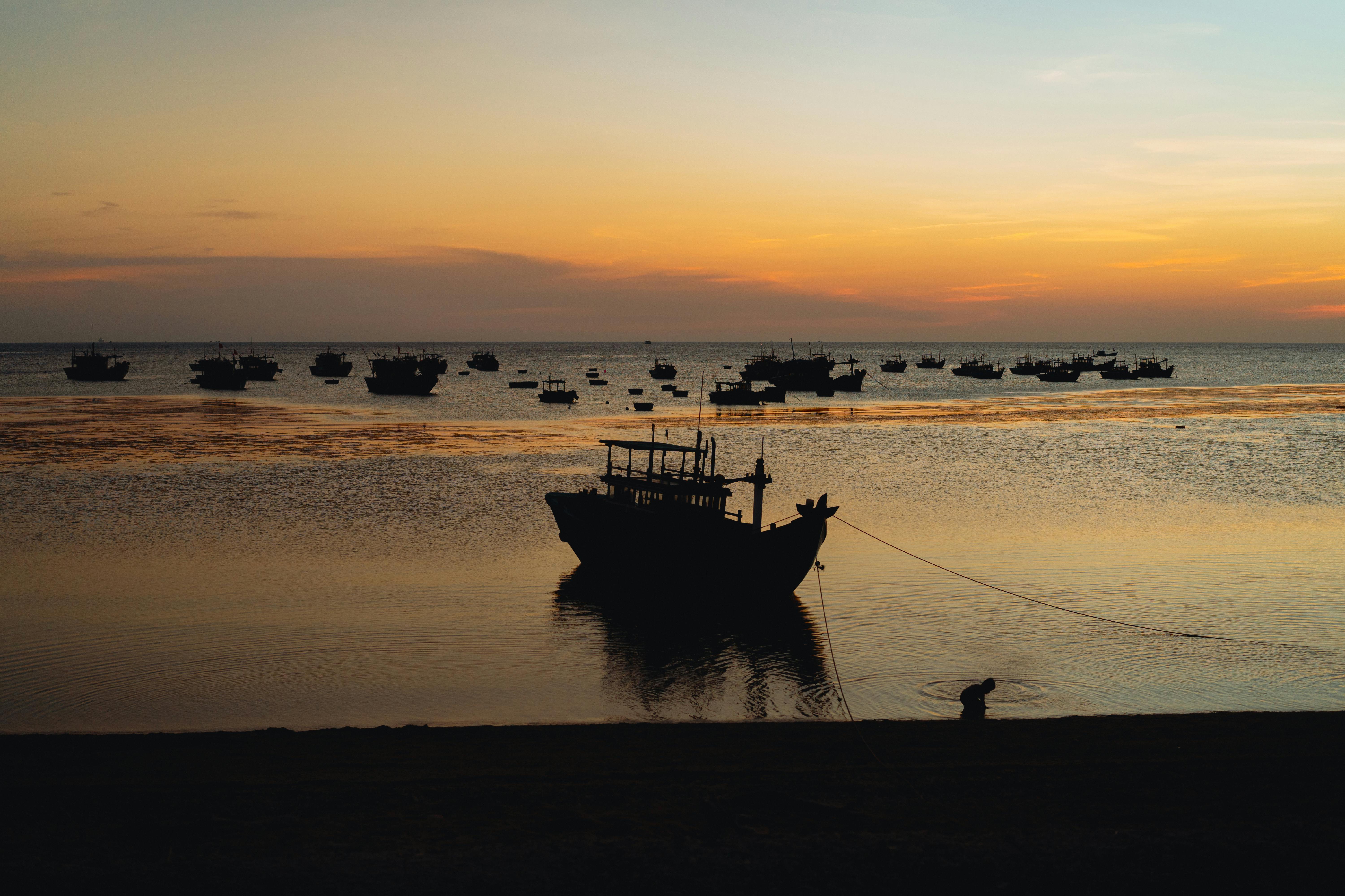 Silhouette of fishing boats at sunset in Bình Thuận, Vietnam. Peaceful evening seascape.
