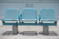 香港城市环境中，一把空蓝色的金属座椅油漆剥落，未见球类运动标志