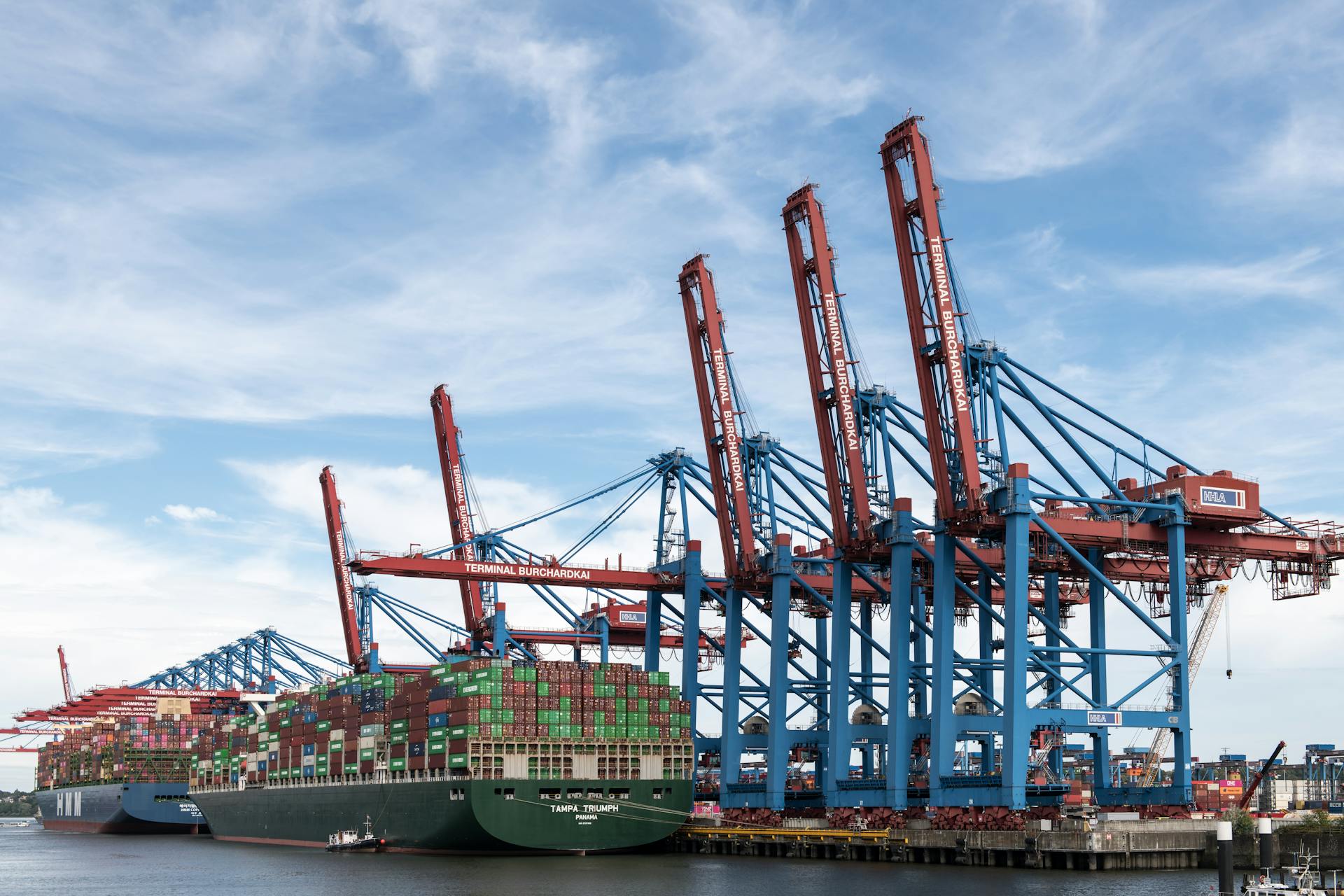 Large container ships docked at Hamburg's bustling port under a clear blue sky.