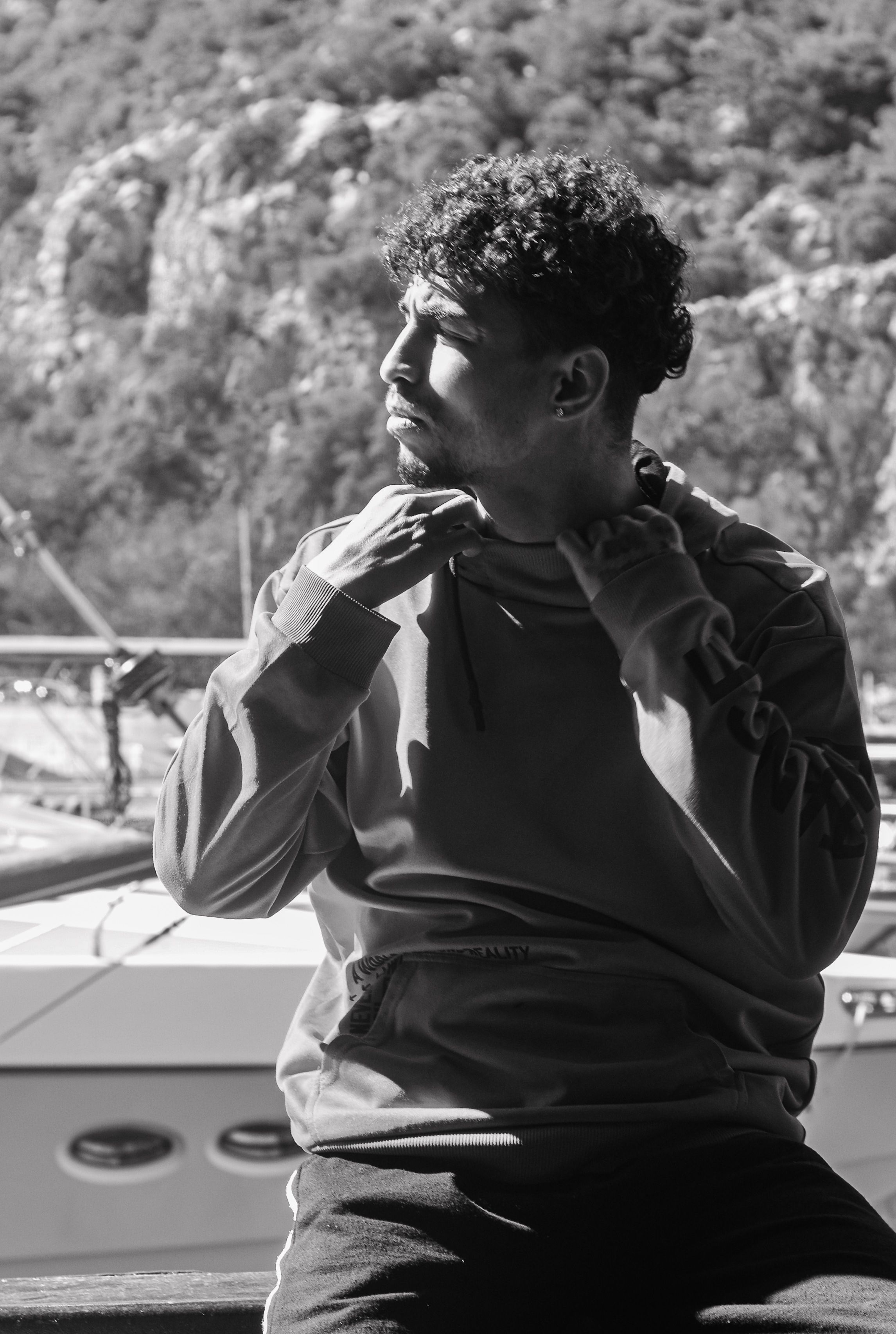 Black and white portrait of a young man sitting by a yacht in Antalya, Türkiye.