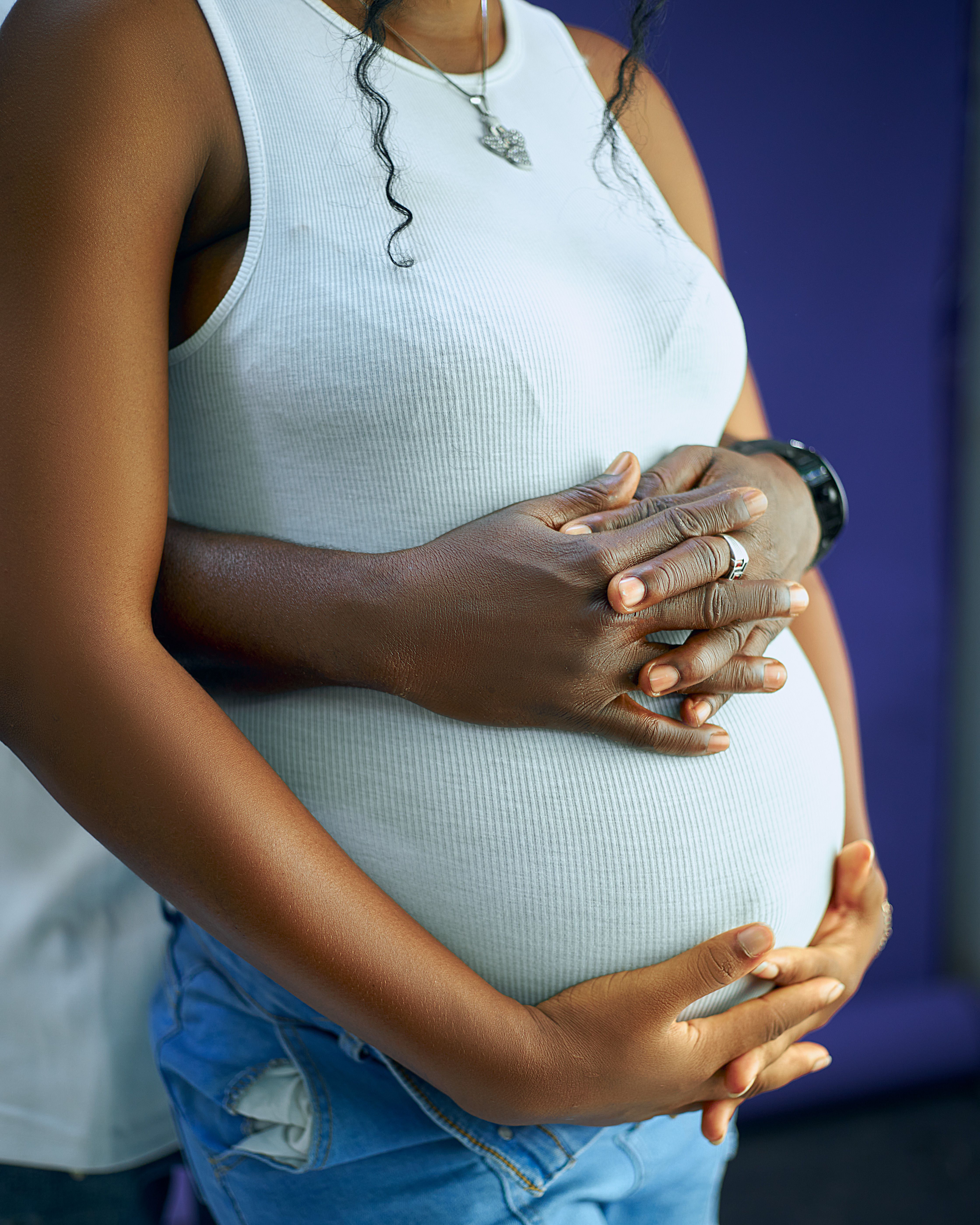 Close-up of loving embrace around pregnant woman's belly, symbolizing care and anticipation.