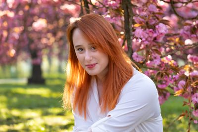 Woman smiling among pink cherry blossoms, photo by Rohit Verma on Pexels